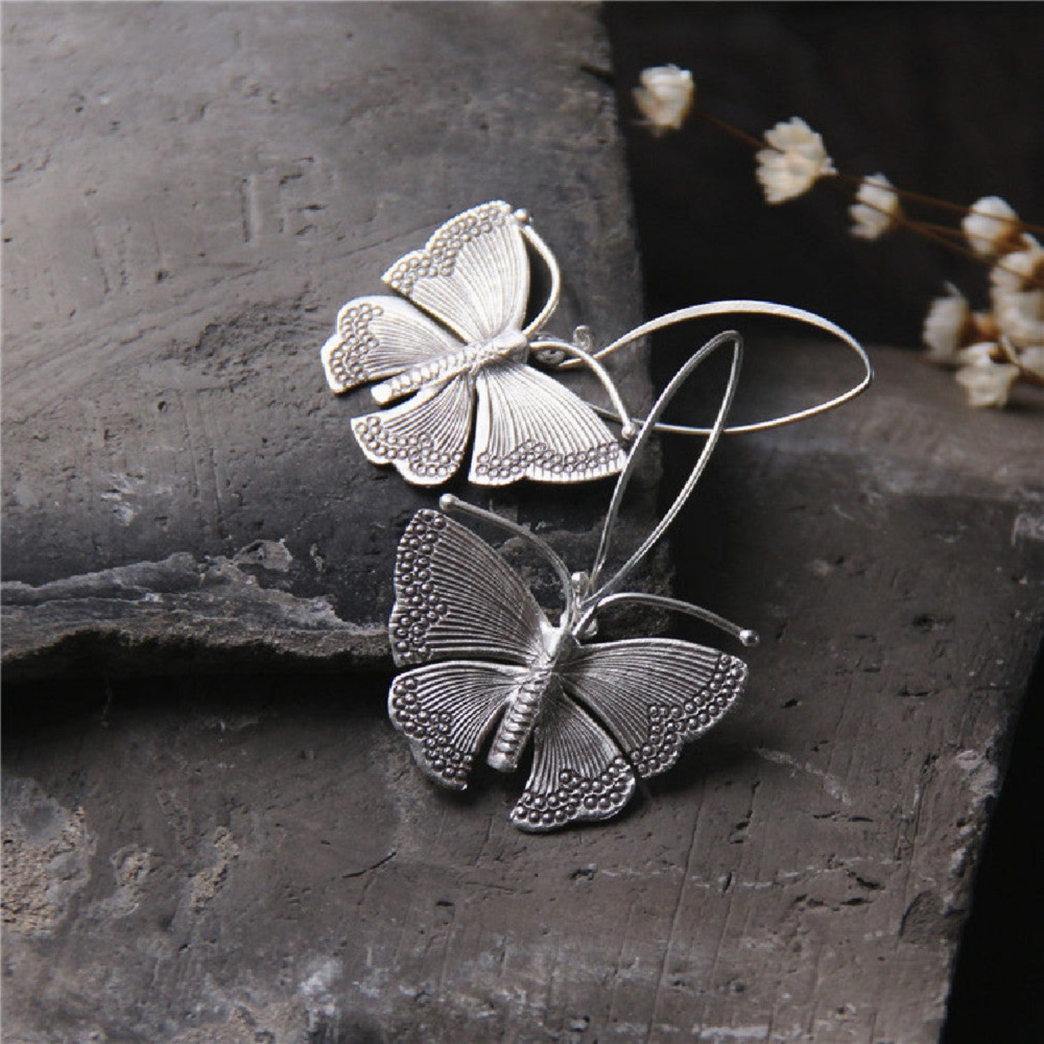 Pair of sterling silver Moonshadow Moth earrings with French hooks, featuring intricate moth design on a light background.