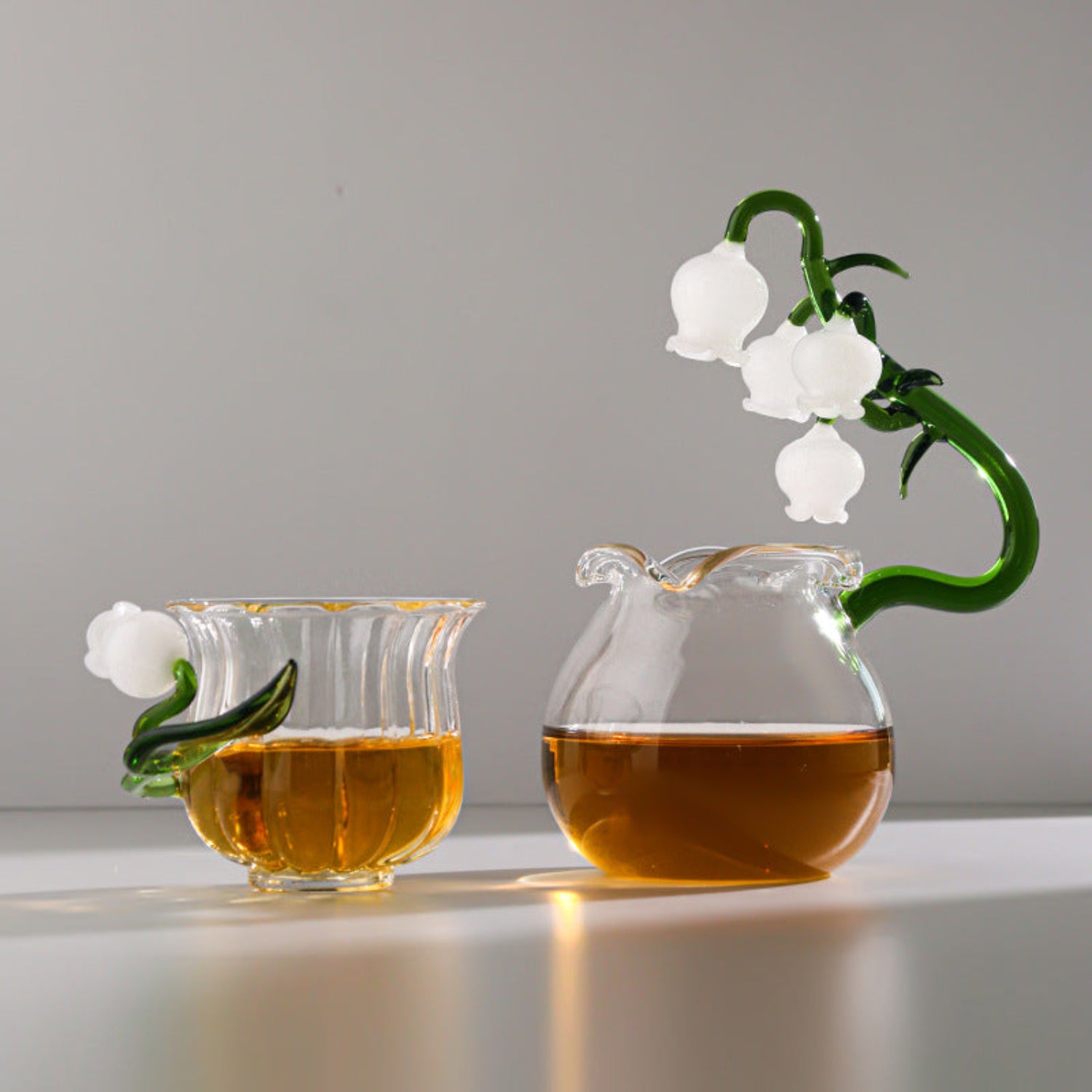 Hand-blown glass bellflower tea set with matching teapot and cup by 24 Hour Crafts, featuring delicate floral design.