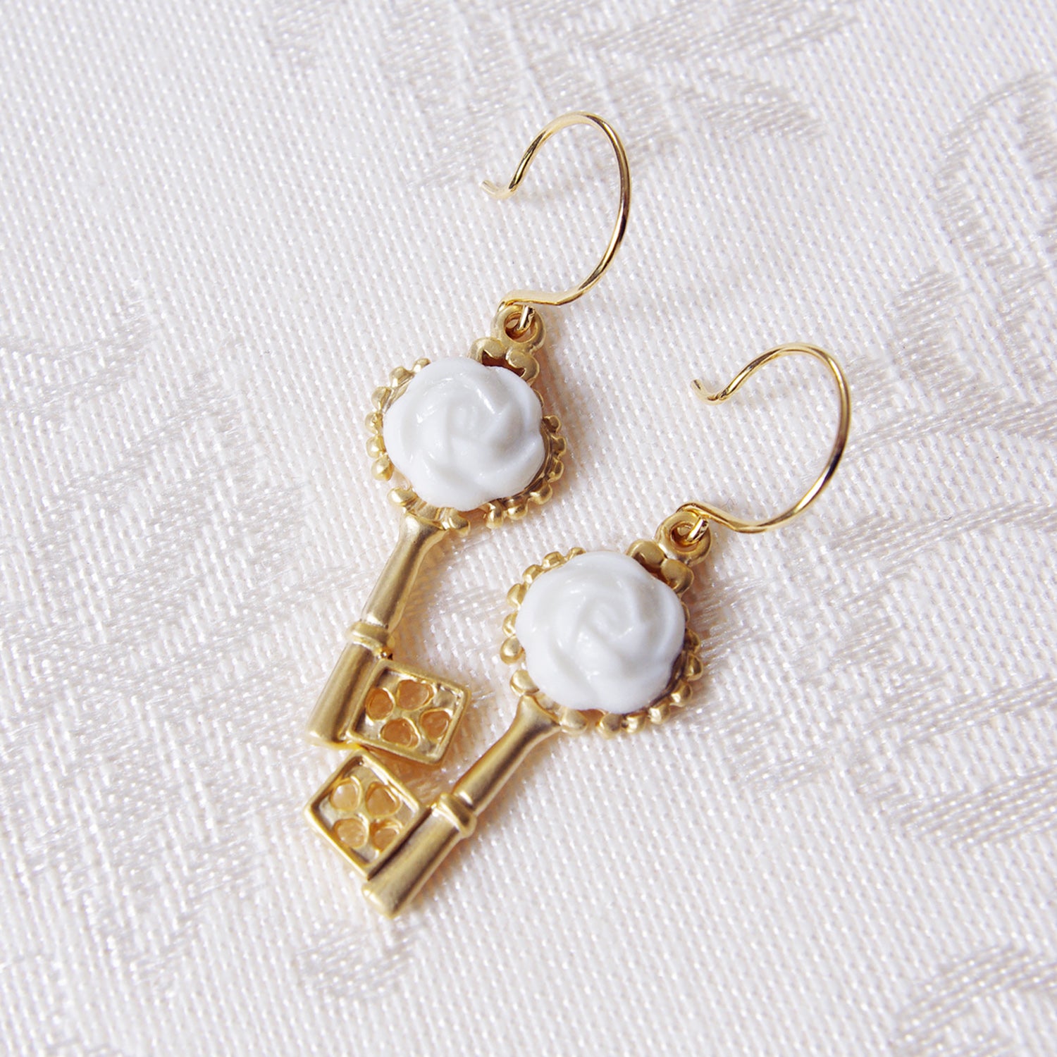 Gold porcelain camellia key earrings from POPORCELAIN's Rosehaven Secret Garden Collection, front view showing intricate floral design.