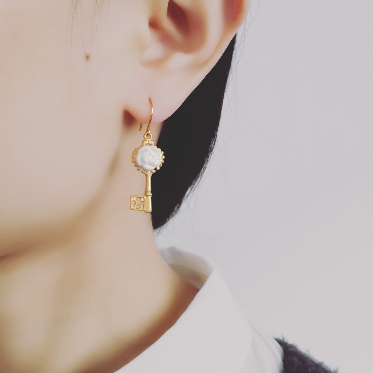 Model wearing POPORCELAIN Porcelain Camellia Golden Key earrings from the Rosehaven Secret Garden jewelry collection.