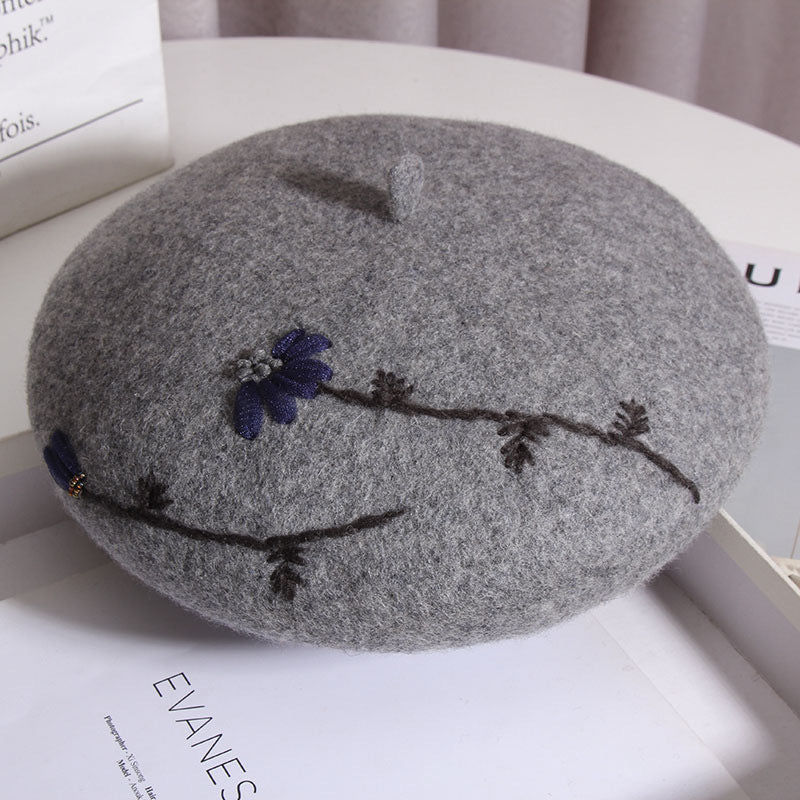 Soft gray mushroom meadow daisy beret with embroidered mushroom cap silhouette and daisy design around the brim, stylish cottagecore hat.