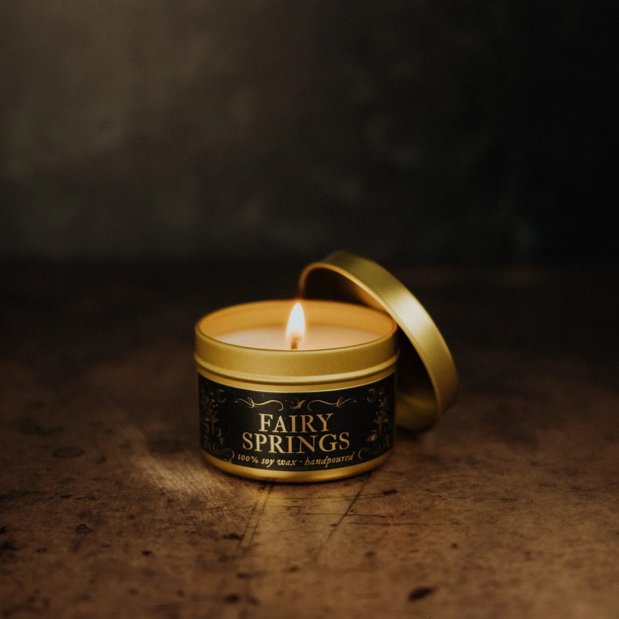 Fairy Springs Candle by Phantom Row in a tin container, featuring a whimsical fairy design with a lit candle inside.