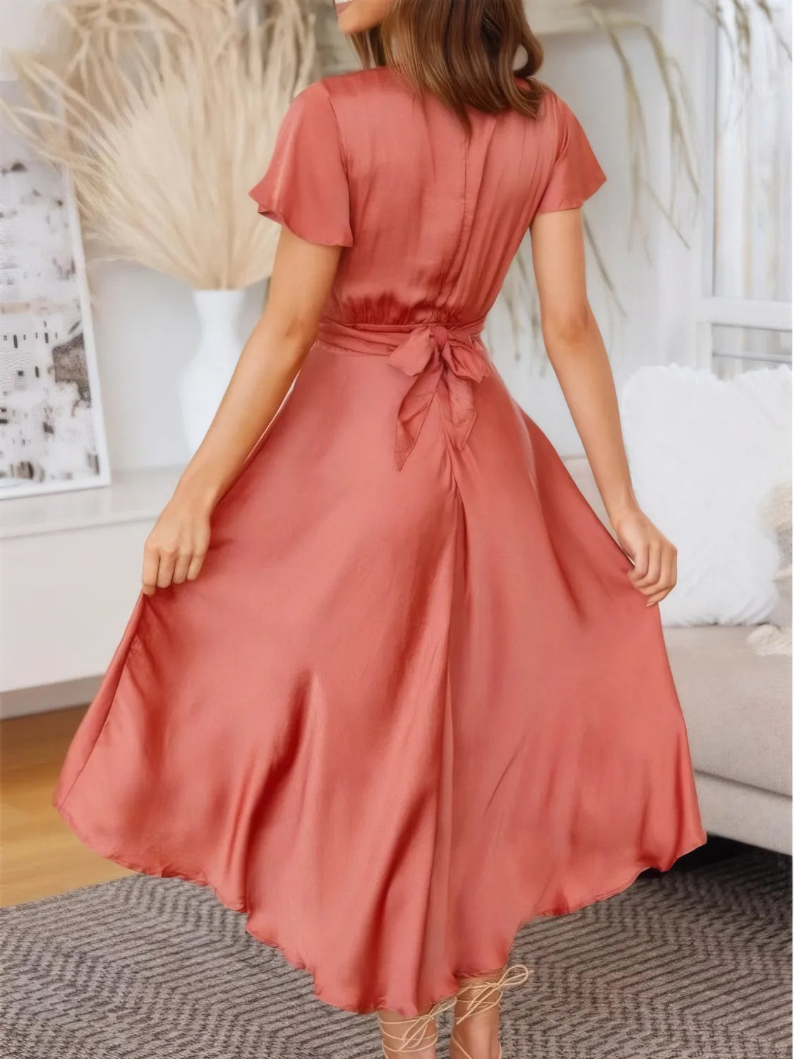 Coral Flutter Skies high-low dress with plunge neckline and crisscross back, worn by a model showcasing its flowing design.