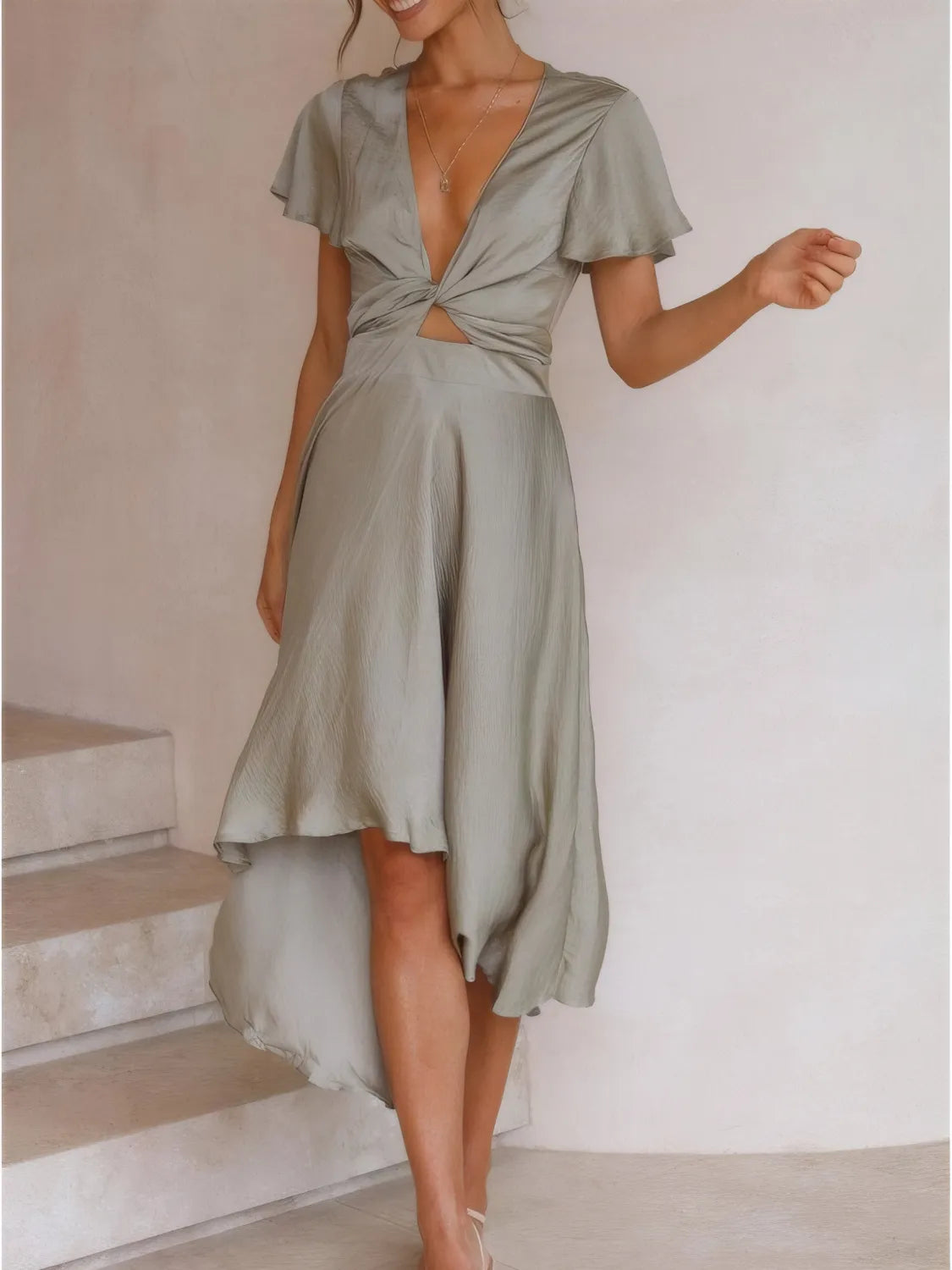 Sage green Flutter Skies high-low dress by Trendsi with plunge neckline and crisscross back, worn by a model.